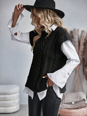 Poncho zwart gebreid met kabelpatroon, model draagt witte blouse en hoed, zijprofiel
