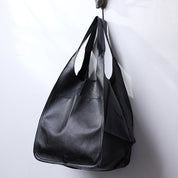 Black slouchy tote with large exterior pockets, hanging view
