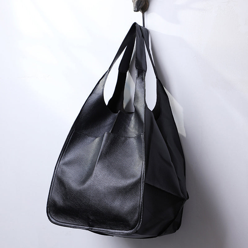 Black slouchy tote with large exterior pockets, hanging view
