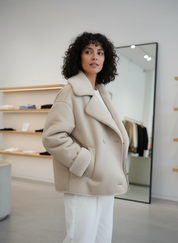Cream teddy-lined coat side view with white pants