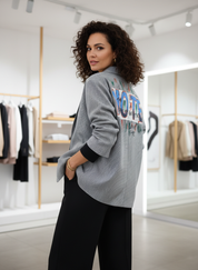 Gray blazer with vibrant text details worn with black pants side profile