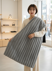 Gray knitted blanket with ribbed texture draped over model in store setting