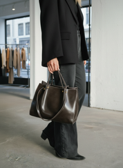 Large brown leather tote bag with contrast stitching, front view.