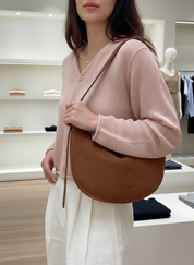 Hobo bag in brown suede held by hand, front view