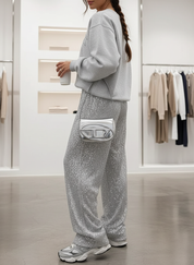 Silver sequin pants with gray sweatshirt and sneakers, side profile