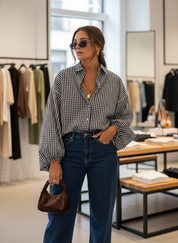 Woman wearing black and white checkered shirt with blue jeans, front view