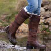 Brown leather knee-high boots stepping out of puddle