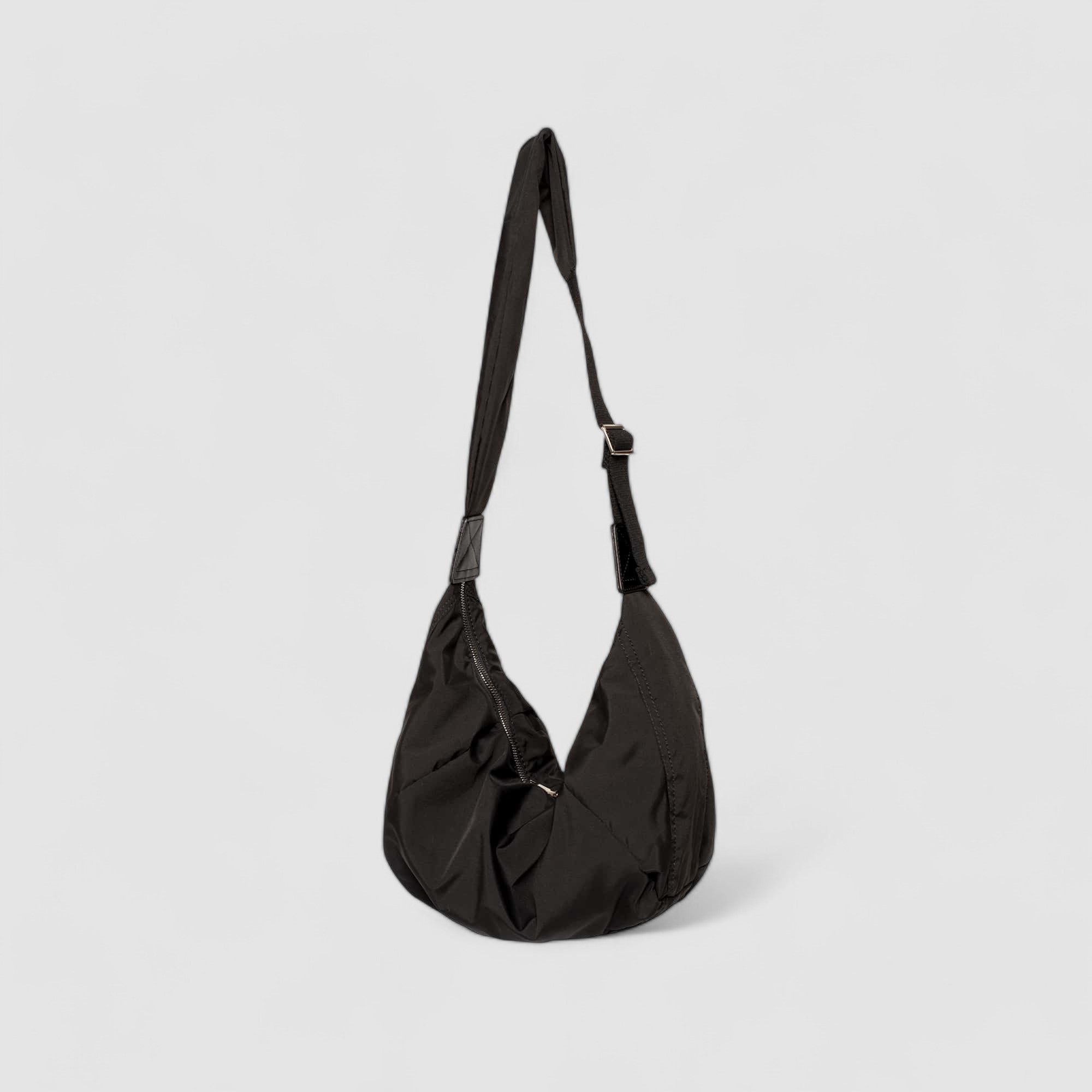 Black shoulder bag with adjustable strap, side view