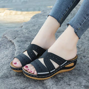 Black leather sandals with floral embroidery worn on feet