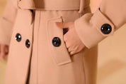 Winterjas beige met zwarte knopen en zakken close-up detail