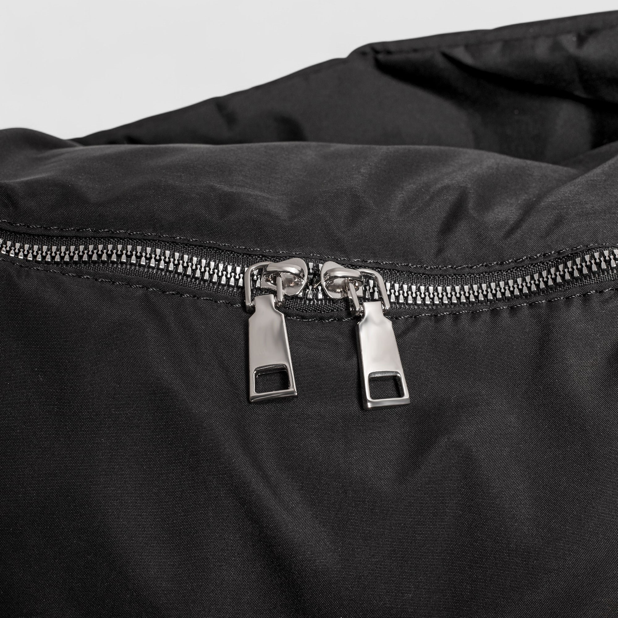 Black shoulder bag zipper with metal pullers, close-up detail
