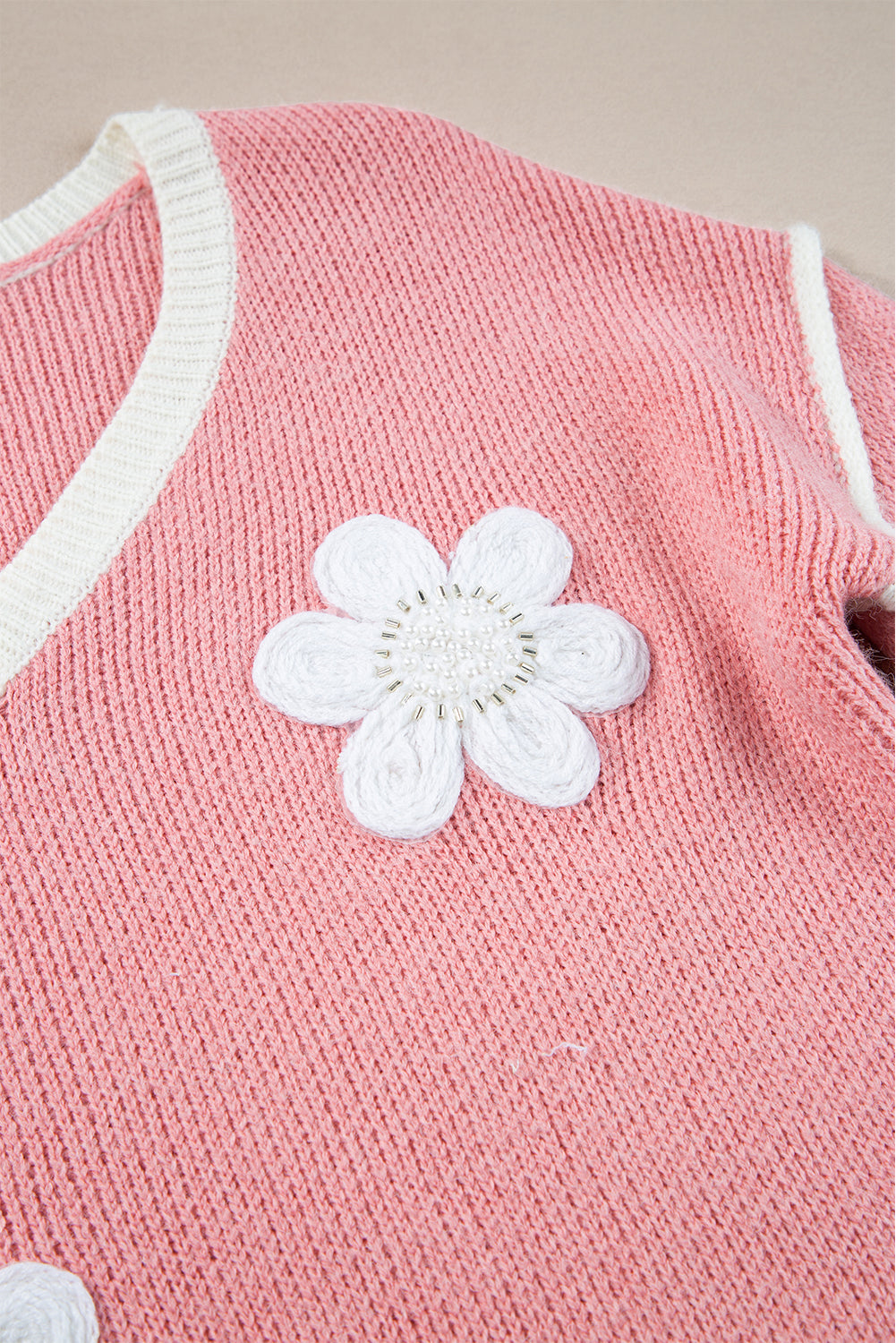 Rosa trui met witte bloemdetail en overdunde schouders close-up