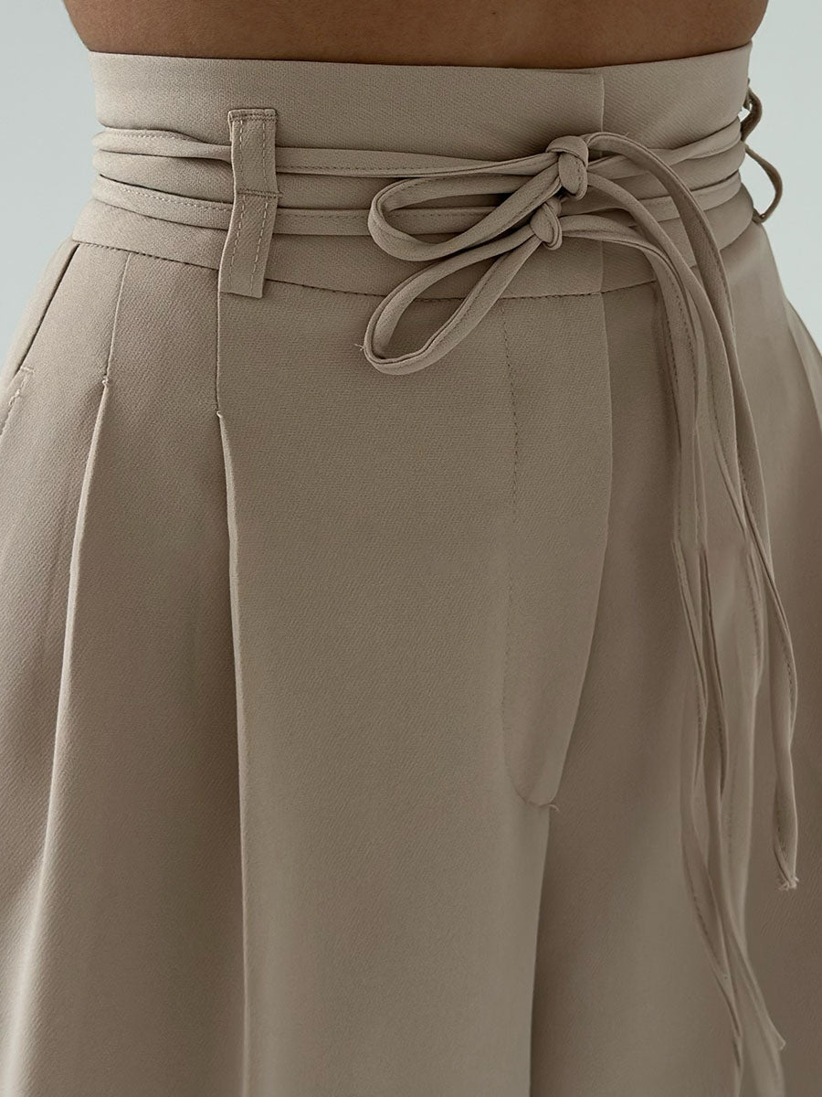 Beige high-waisted pants with tie waist detail close-up