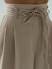 Beige high-waisted pants with tie waist detail close-up