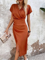 Midi dress orange with V-neck and side slit front view with clutch