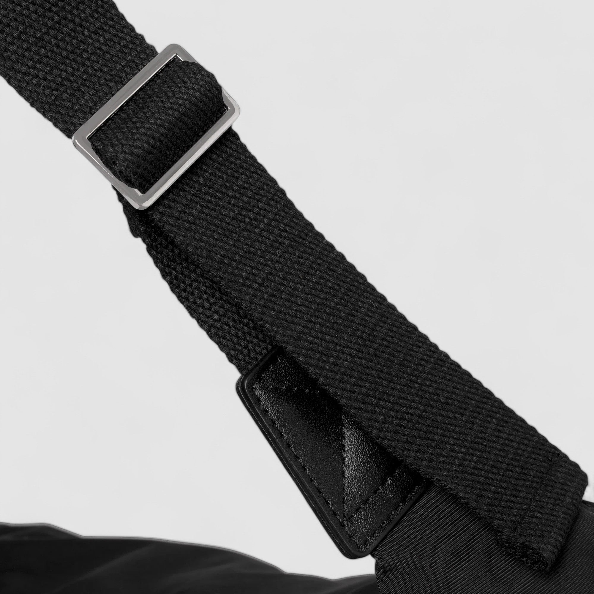 Black shoulder bag strap with metal buckle, close-up detail