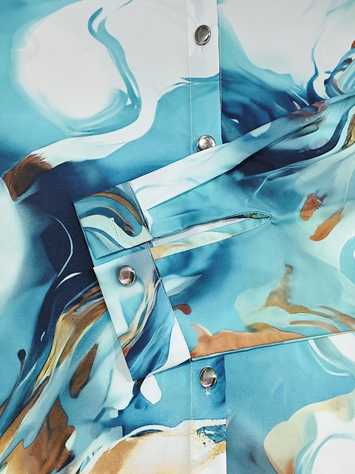 Silk blouse with abstract marbled print, close-up of button detail