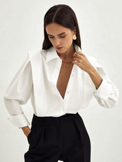 White blouse with deep V-neck and gold jewelry close-up