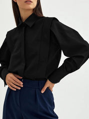 Black blouse with puff sleeves and navy pants detail shot