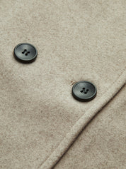 Details van beige jas met zwarte knopen close-up