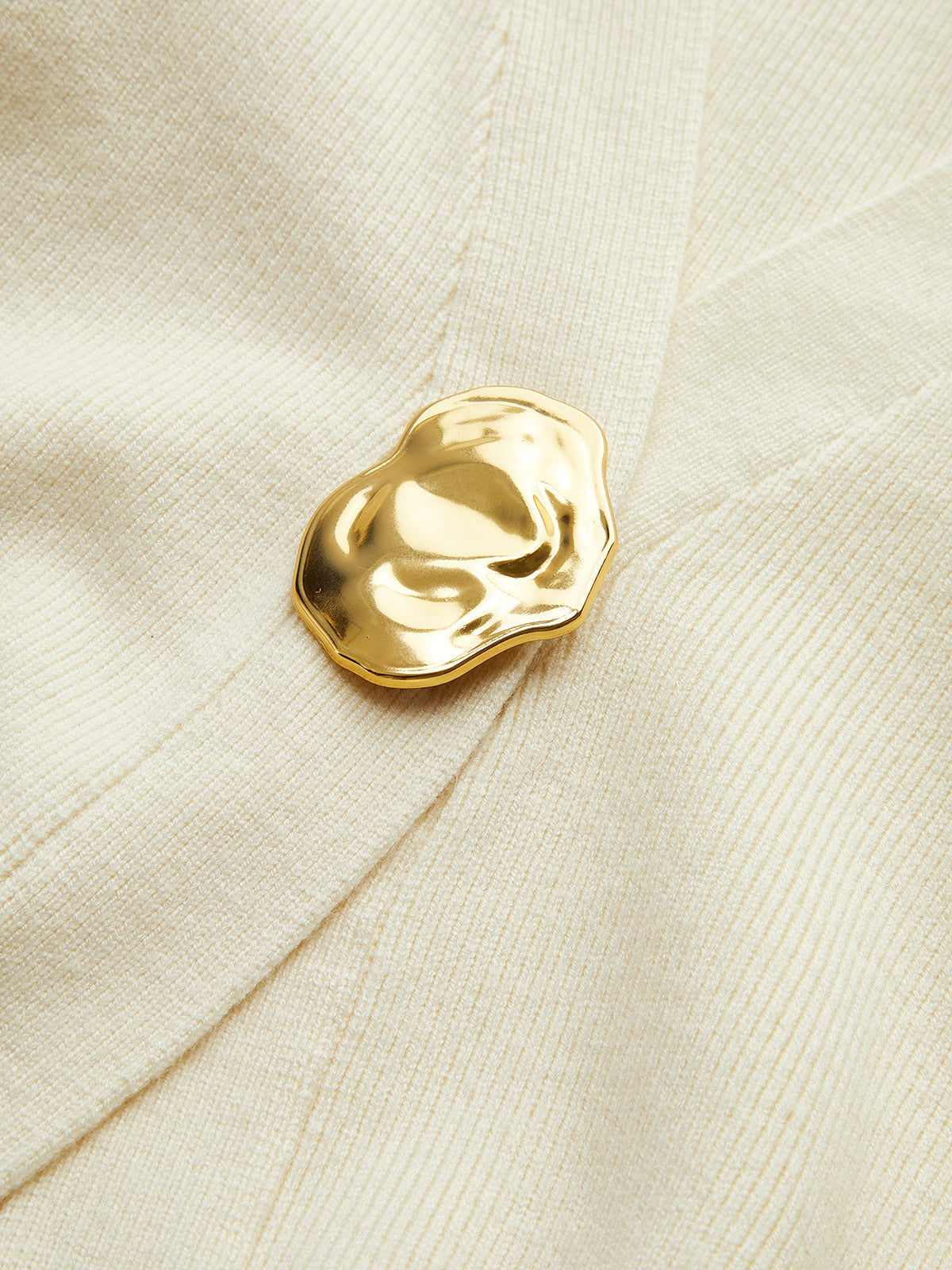 Gouden knoop detail shot op lichtgrijze stof