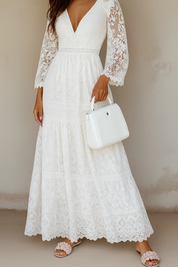 White lace maxi dress with bell sleeves and white handbag, side profile