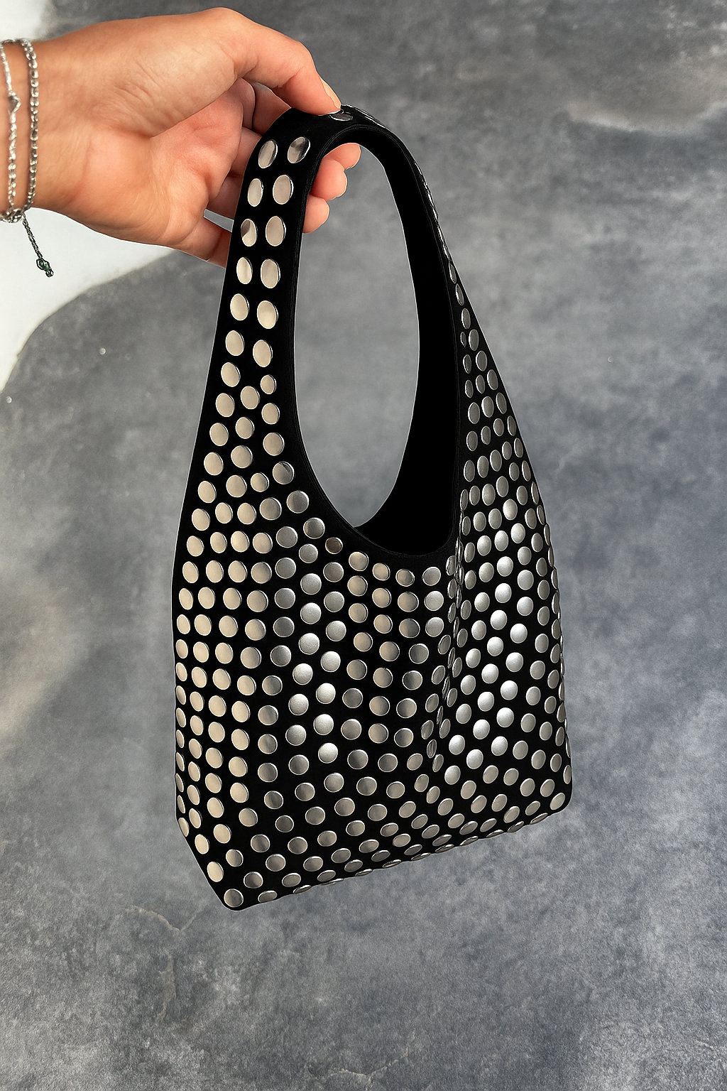 Black hobo bag with silver studs held in hand