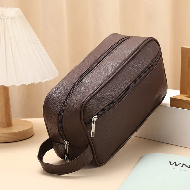 Brown toiletry bag on table with lamp and book
