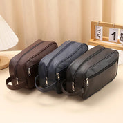 Three toiletry bags in brown, navy, and black side-by-side