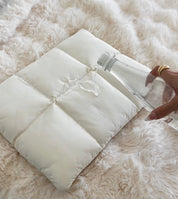 Witte puffer laptophoes op zachte deken detailopname