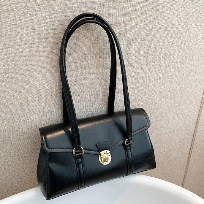Black vegan leather shoulder bag on white surface