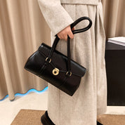 Black vegan leather shoulder bag held by hand