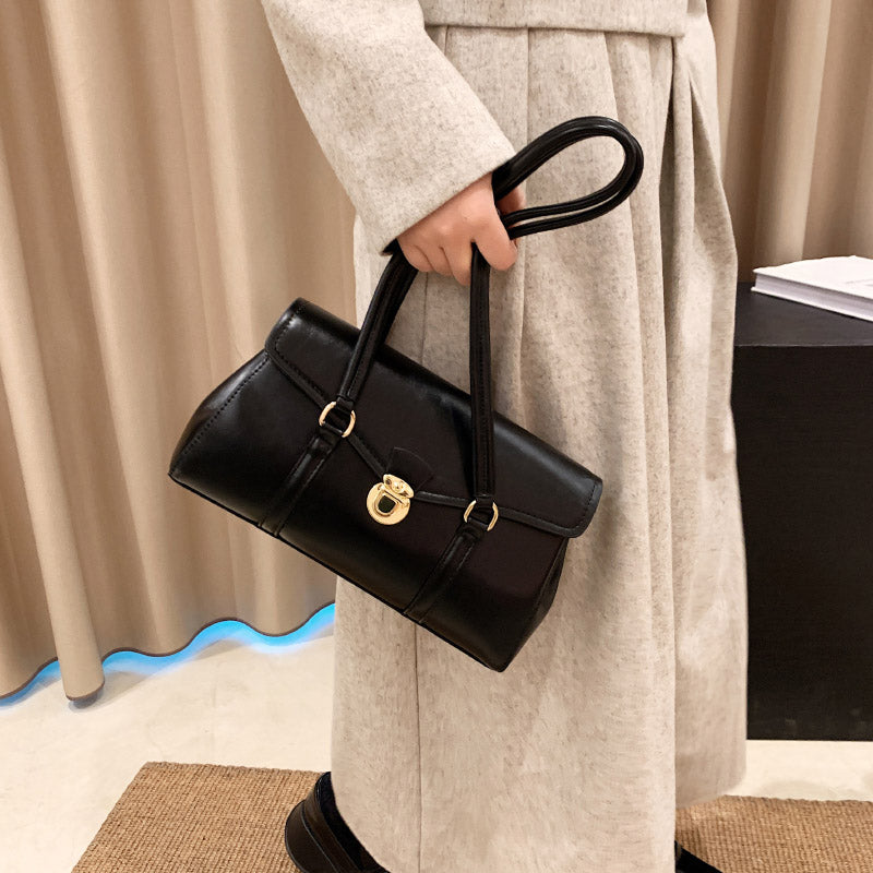 Black vegan leather shoulder bag held by hand