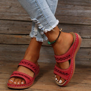 Red leather sandals with cutout details worn on feet