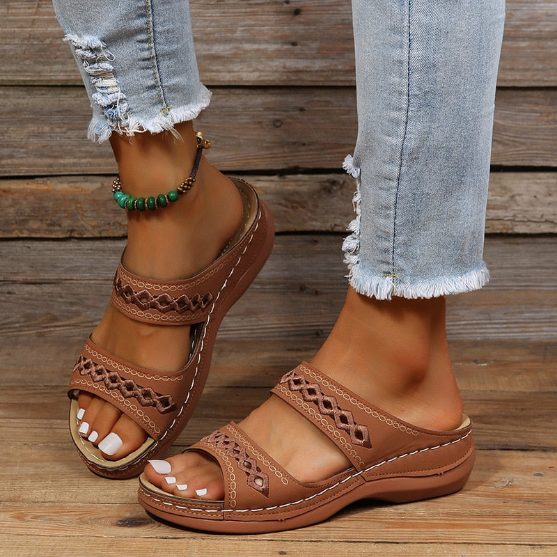 Brown leather sandals with cutout details worn on feet