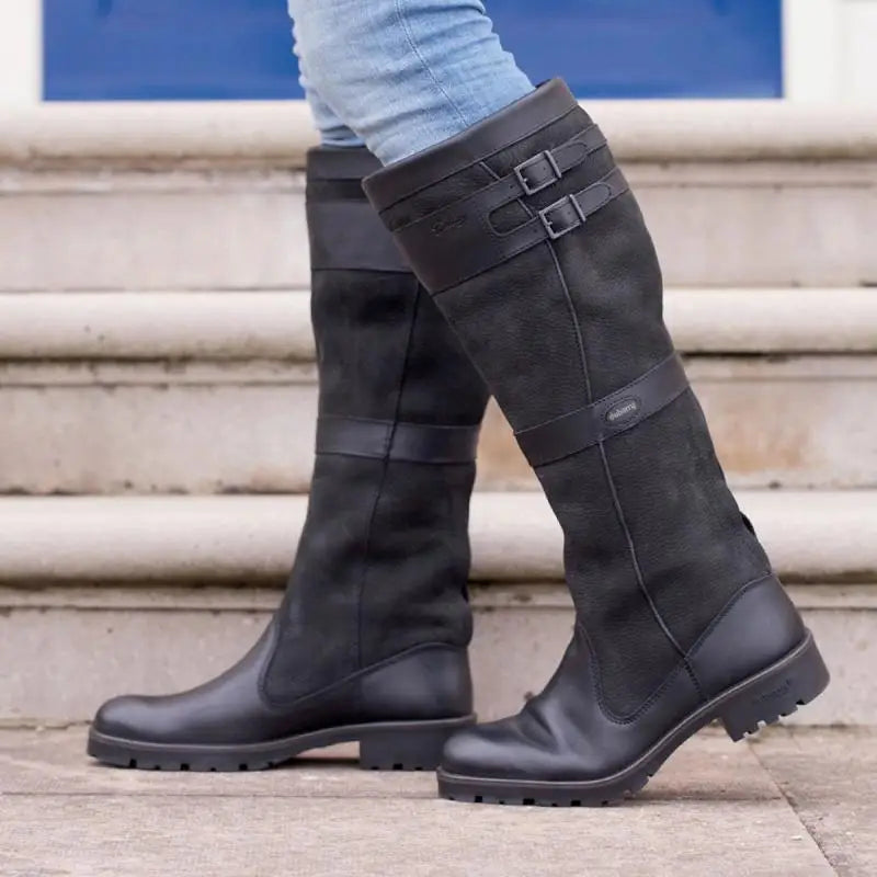Black leather knee-high boots with buckle detail, worn on steps