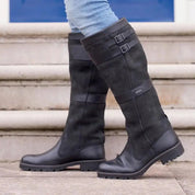 Black leather knee-high boots with buckle detail, worn on steps