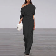 Black jumpsuit with asymmetrical shoulder and wide legs, studio front view