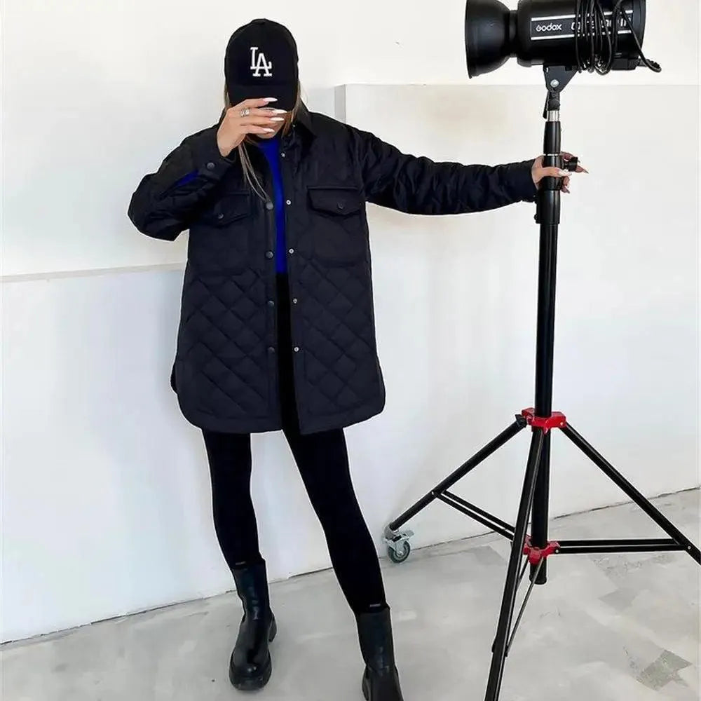 Dames gewatteerde jas zwart met knoopsluiting en zakken, model draagt baseballpet, studio-opname