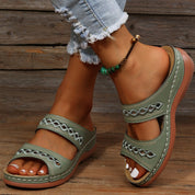 Light green leather sandals with cutout details worn on feet