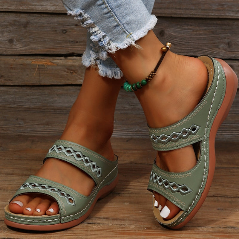Light green leather sandals with cutout details worn on feet