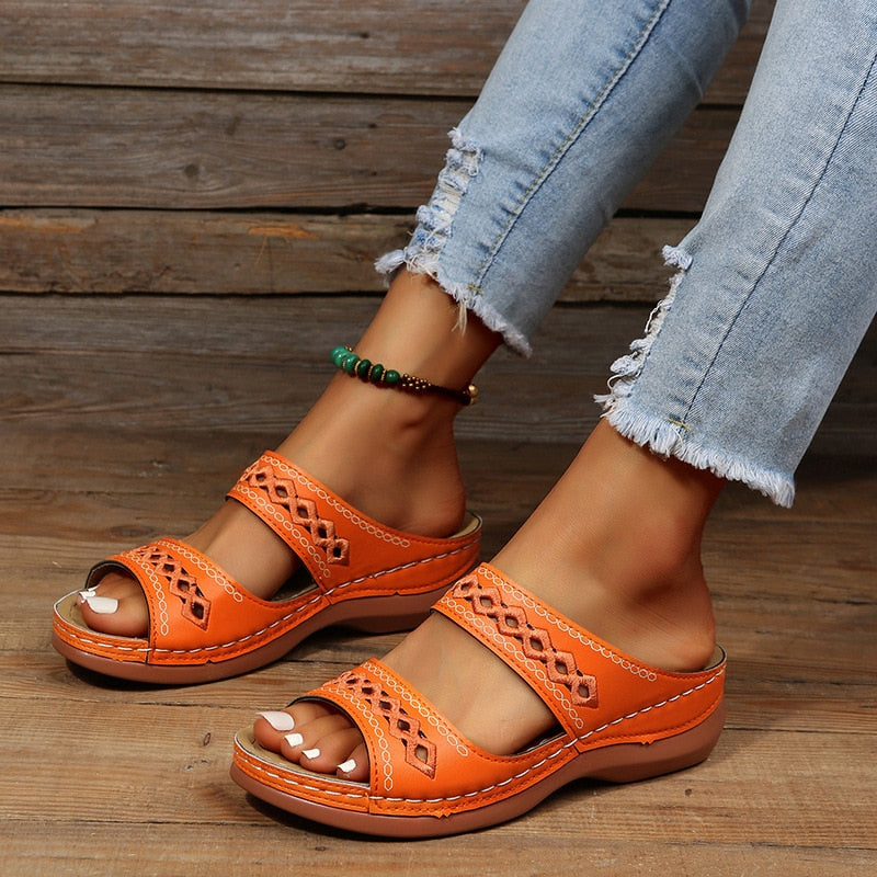 Orange leather sandals with cutout details worn on feet