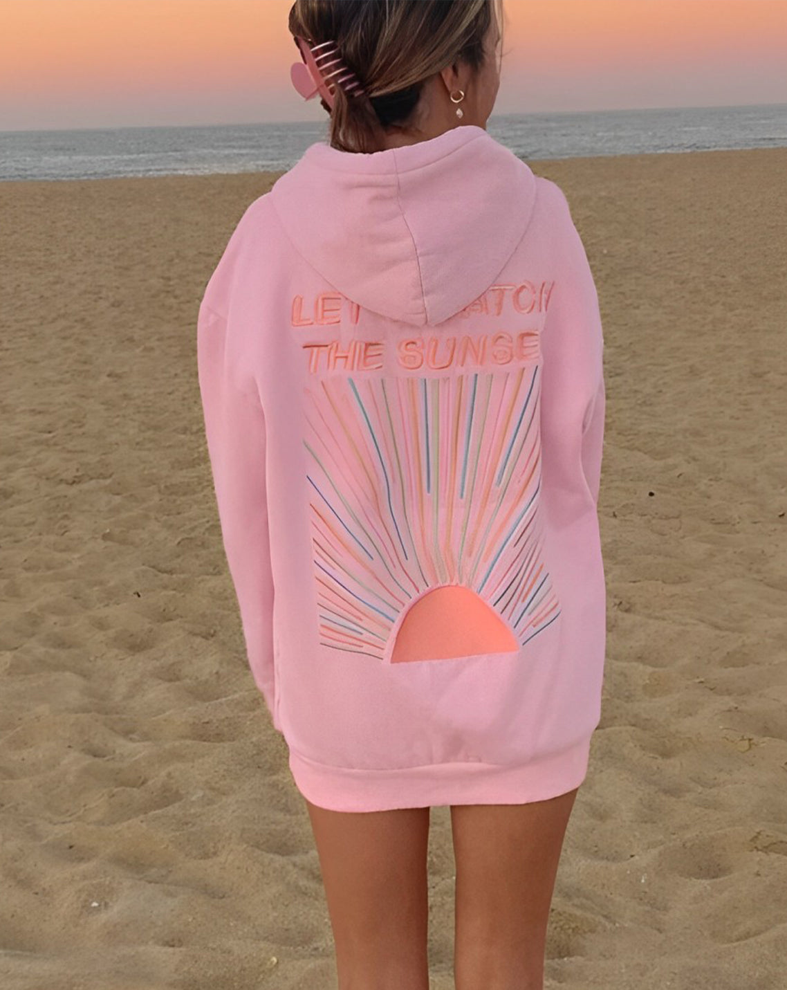 Pink hoodie with sunset design close-up beach setting