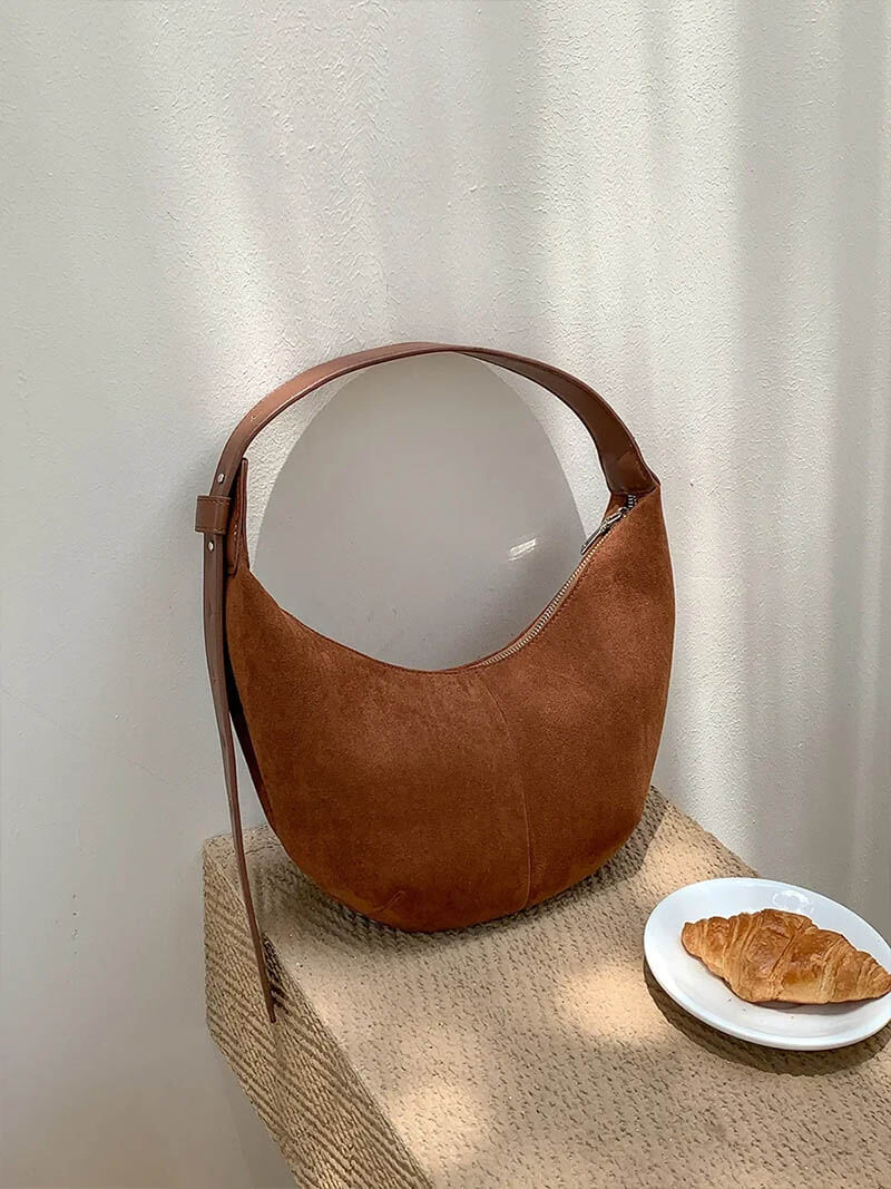 Hobo bag in brown suede on textured surface, front view