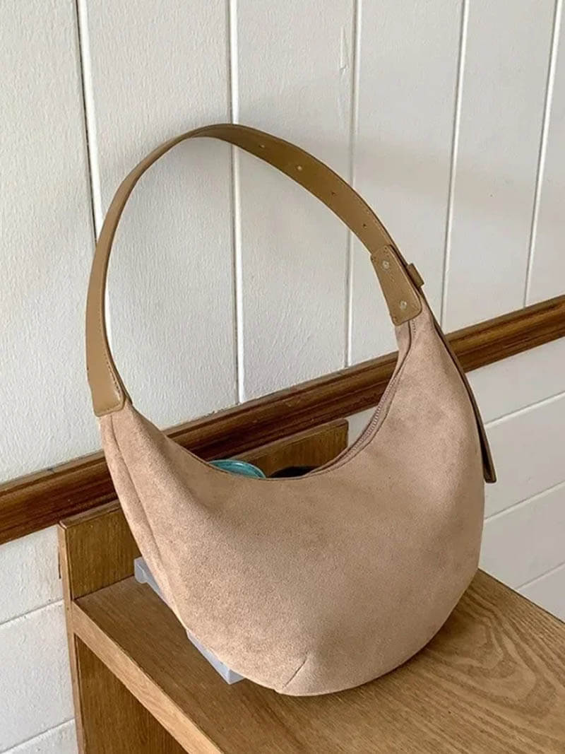 Hobo bag in beige suede on wooden shelf, front view