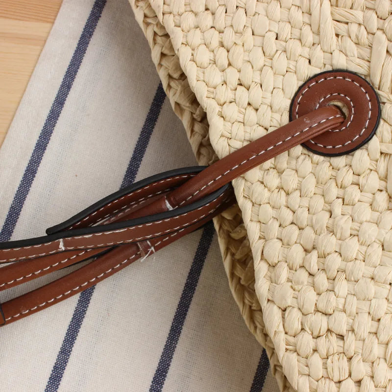 Close-up of woven straw tote bag handle with brown leather accent