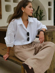 White linen blouse with beige pants, seated pose