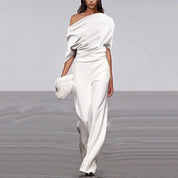 White jumpsuit with draped shoulder and wide legs, studio front view