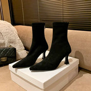 Black suede ankle boots in box, angled view