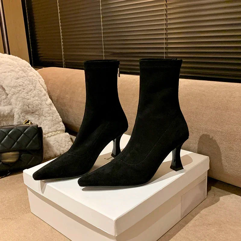 Black suede ankle boots in box, angled view